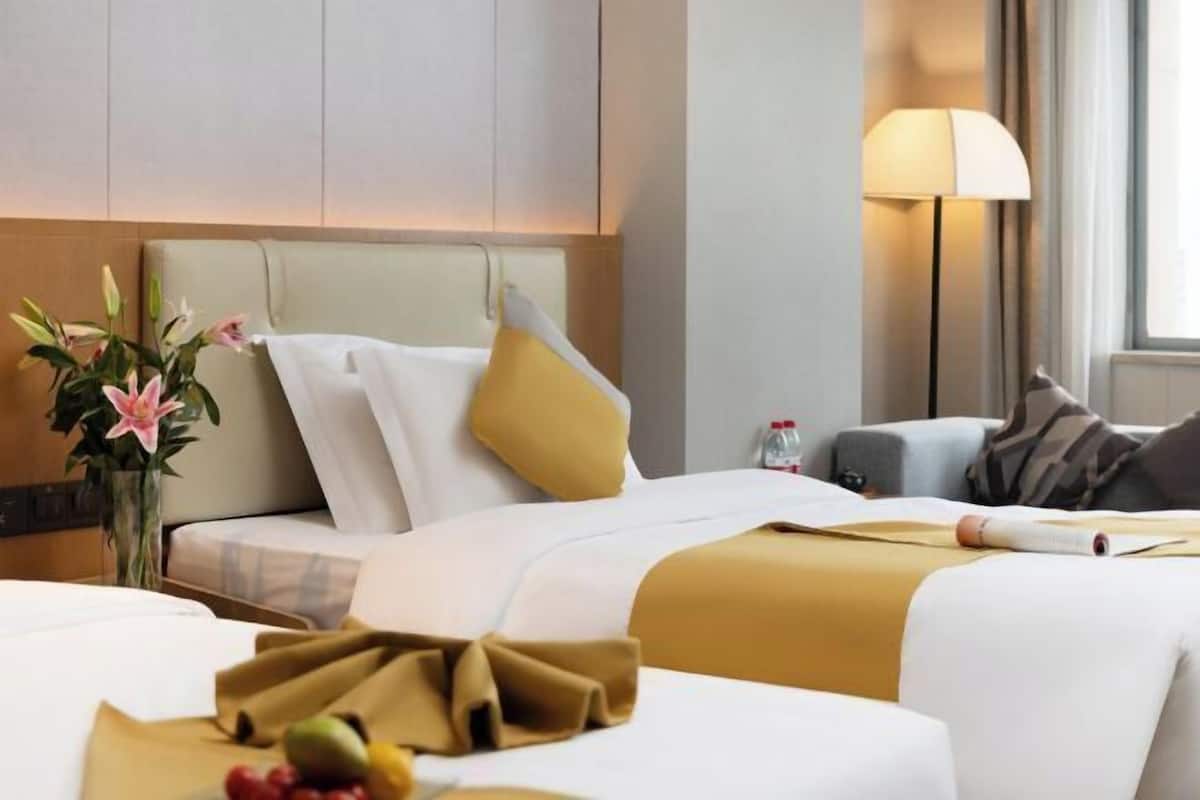 Een hotelkamer met een bed, nachtkastje, lamp en raam.