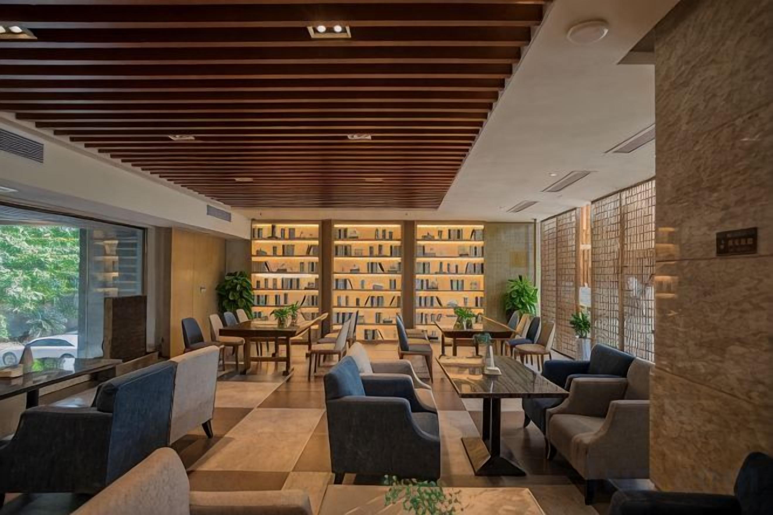 A modern library with bookshelves, seating areas, and a stone wall.