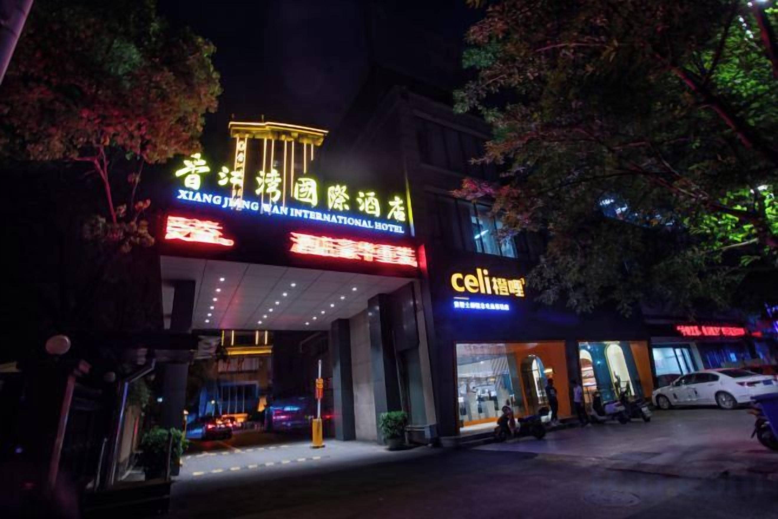 A hotel entrance with illuminated signage, a visible entrance, and a parking area.