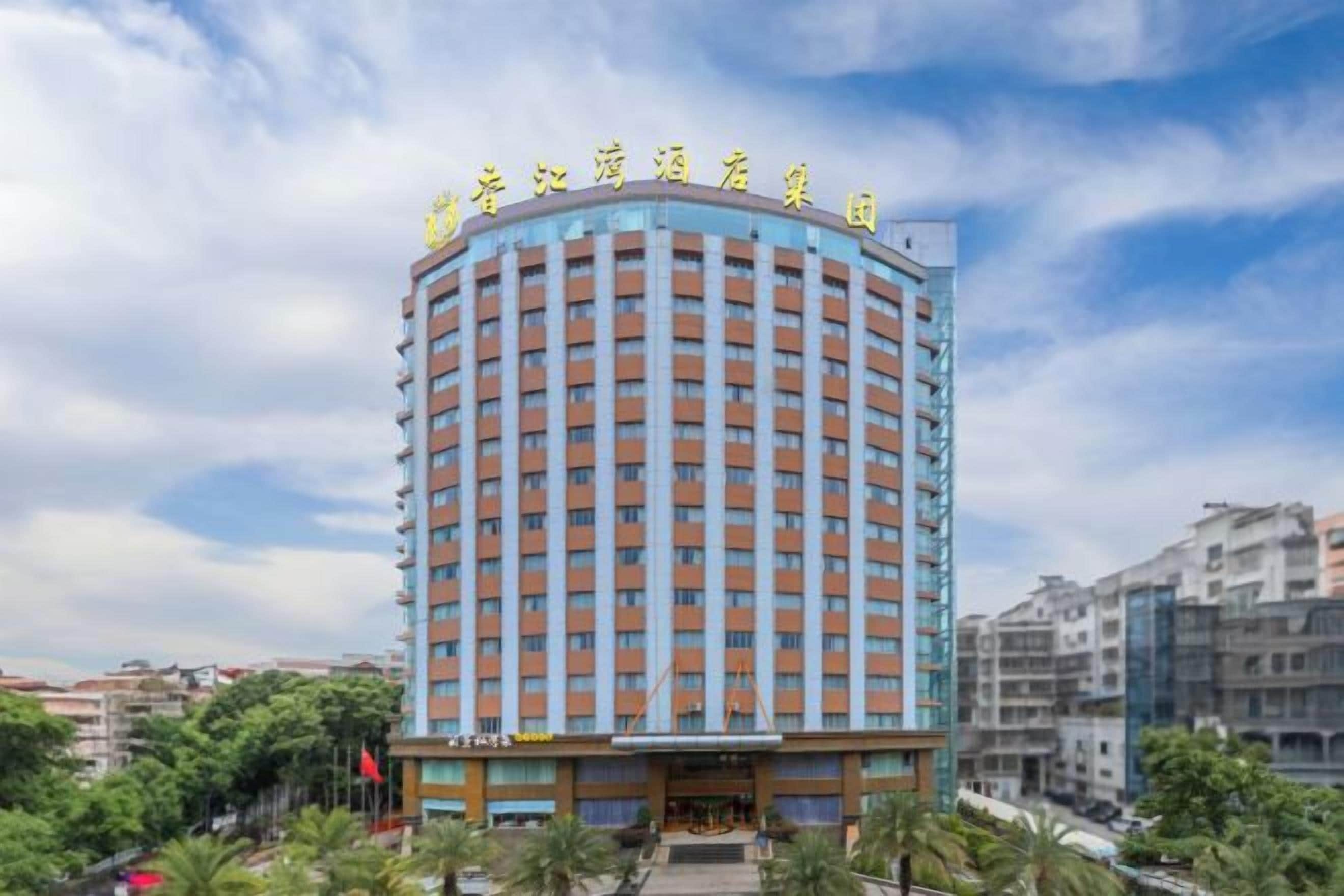 A multi-story hotel with a curved facade, a prominent entrance, and a flagpole.