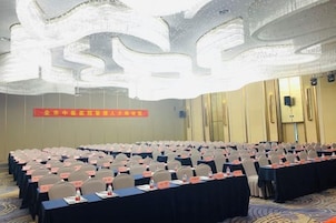 Un salón de conferencias con mesas dispuestas en filas, sillas, tarjetas de identificación y botellas de agua.