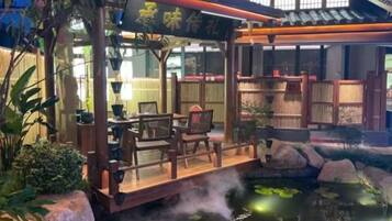 Un restaurante tradicional japonés con terraza de madera que da a un estanque con peces koi.