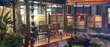 A traditional Japanese-style restaurant with a wooden deck overlooking a koi pond.