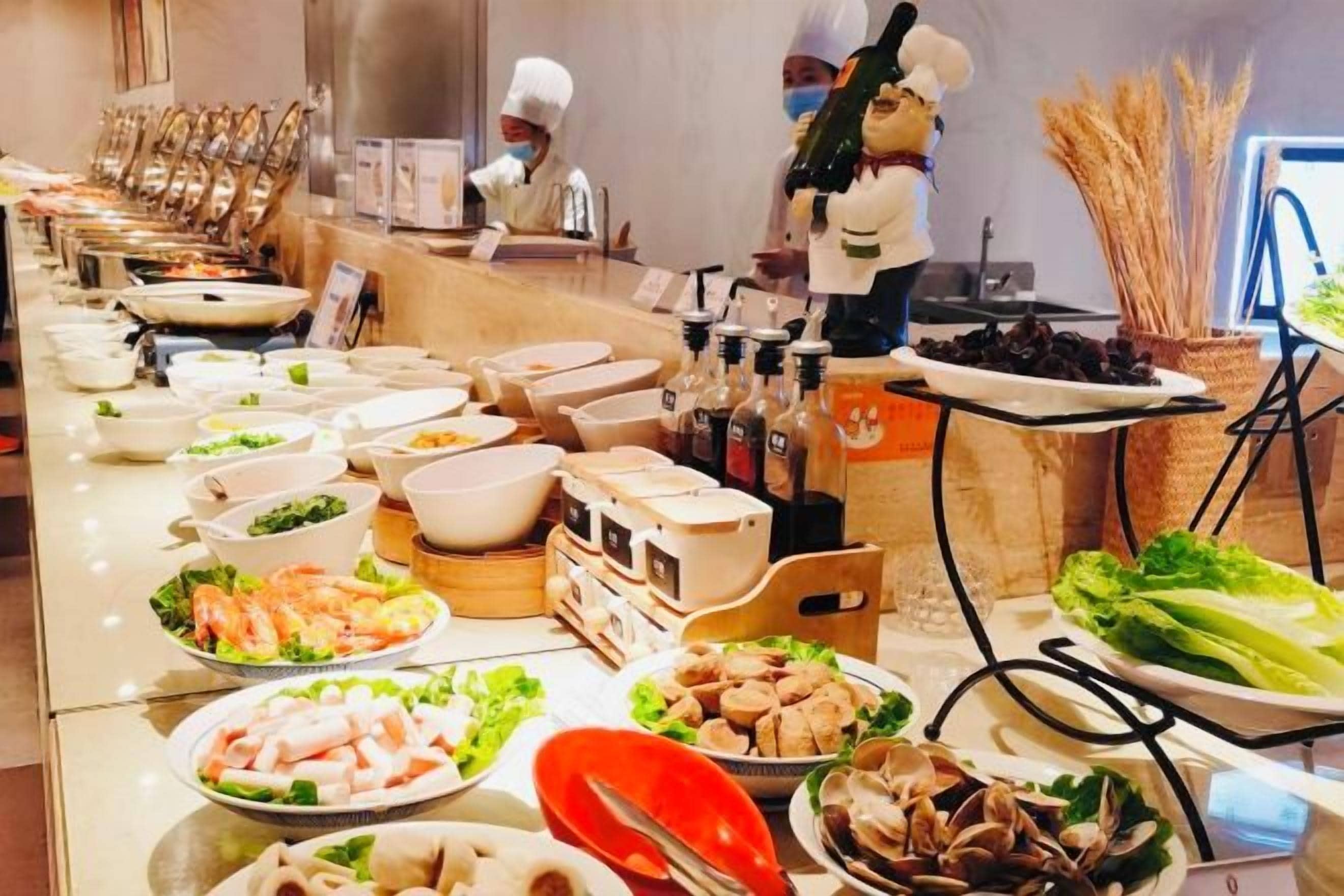 A buffet setup with various food items and a chef in the background.