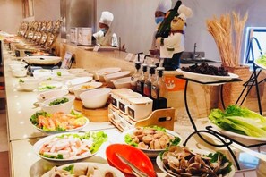 Un buffet proposant une variété de plats, avec un chef cuisinier en arrière-plan.