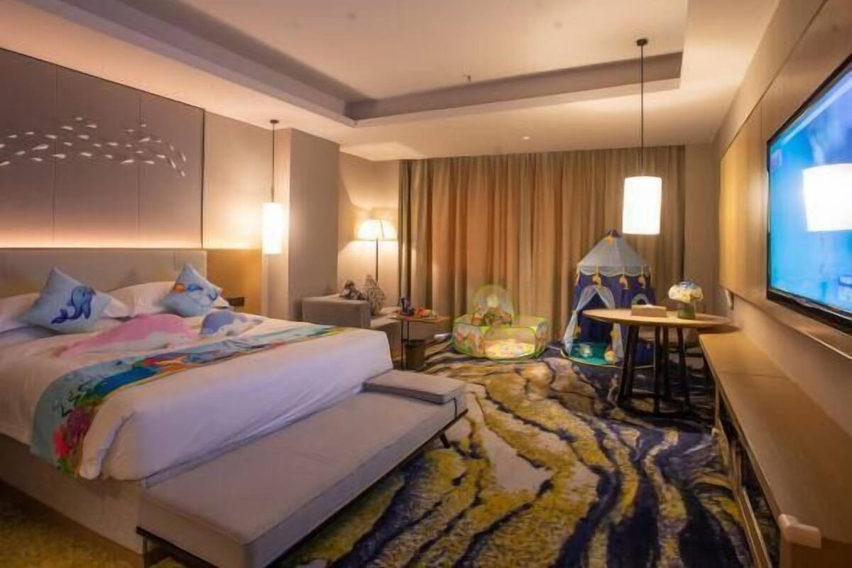 Een hotelkamer met een groot bed, een flatscreen televisie, een bureau en een stoel.