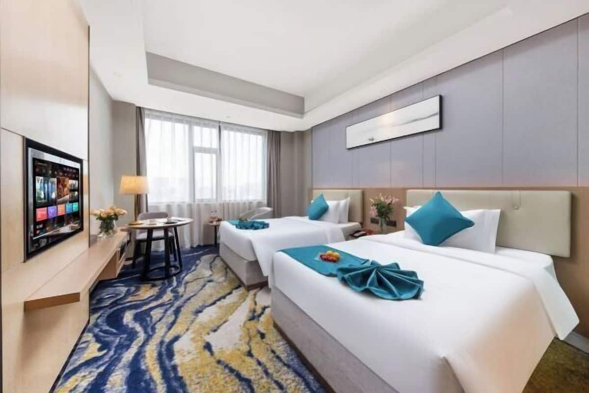Een hotelkamer met twee bedden, een televisie, een bureau en een raam.
