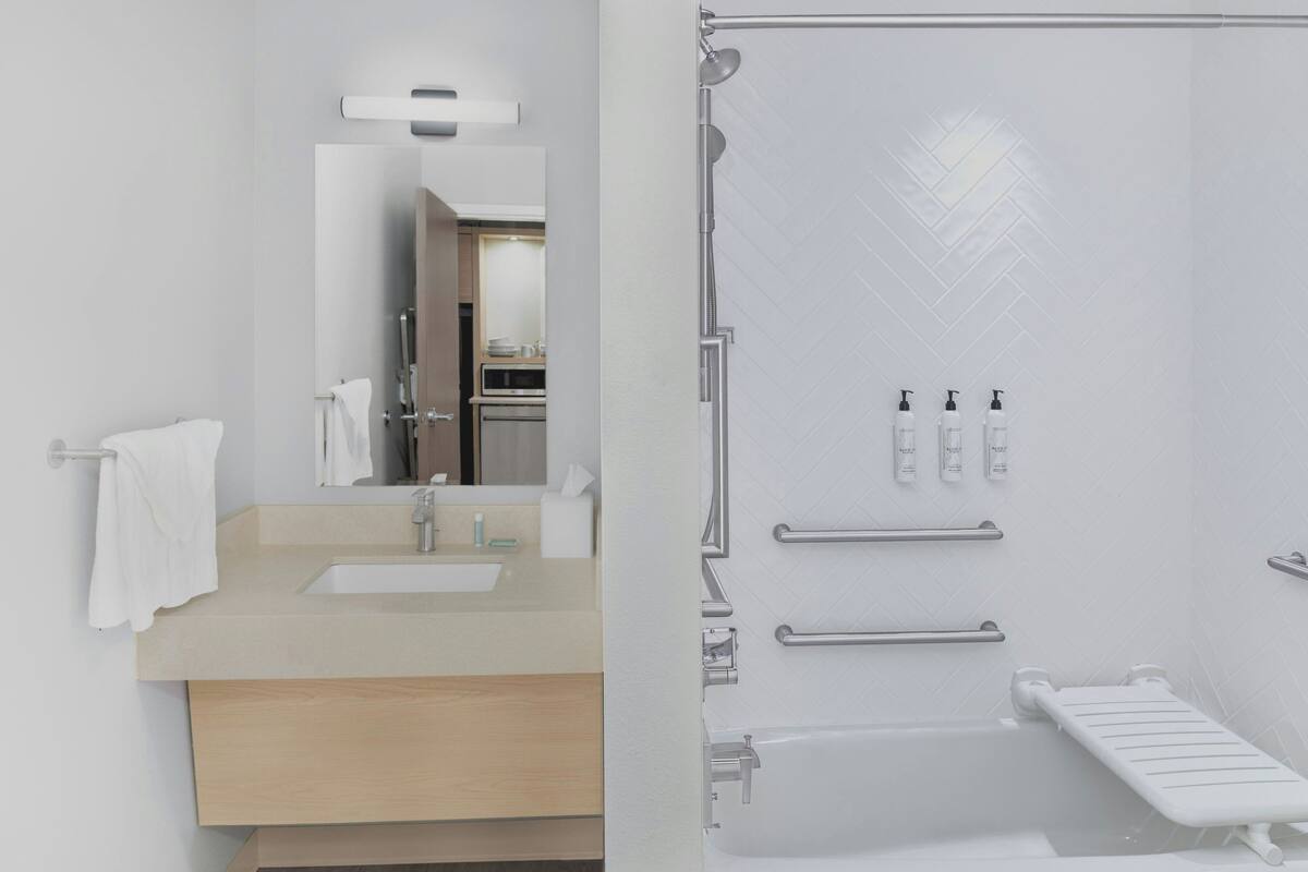 Un baño moderno con lavamanos, espejo e inodoro con ducha.