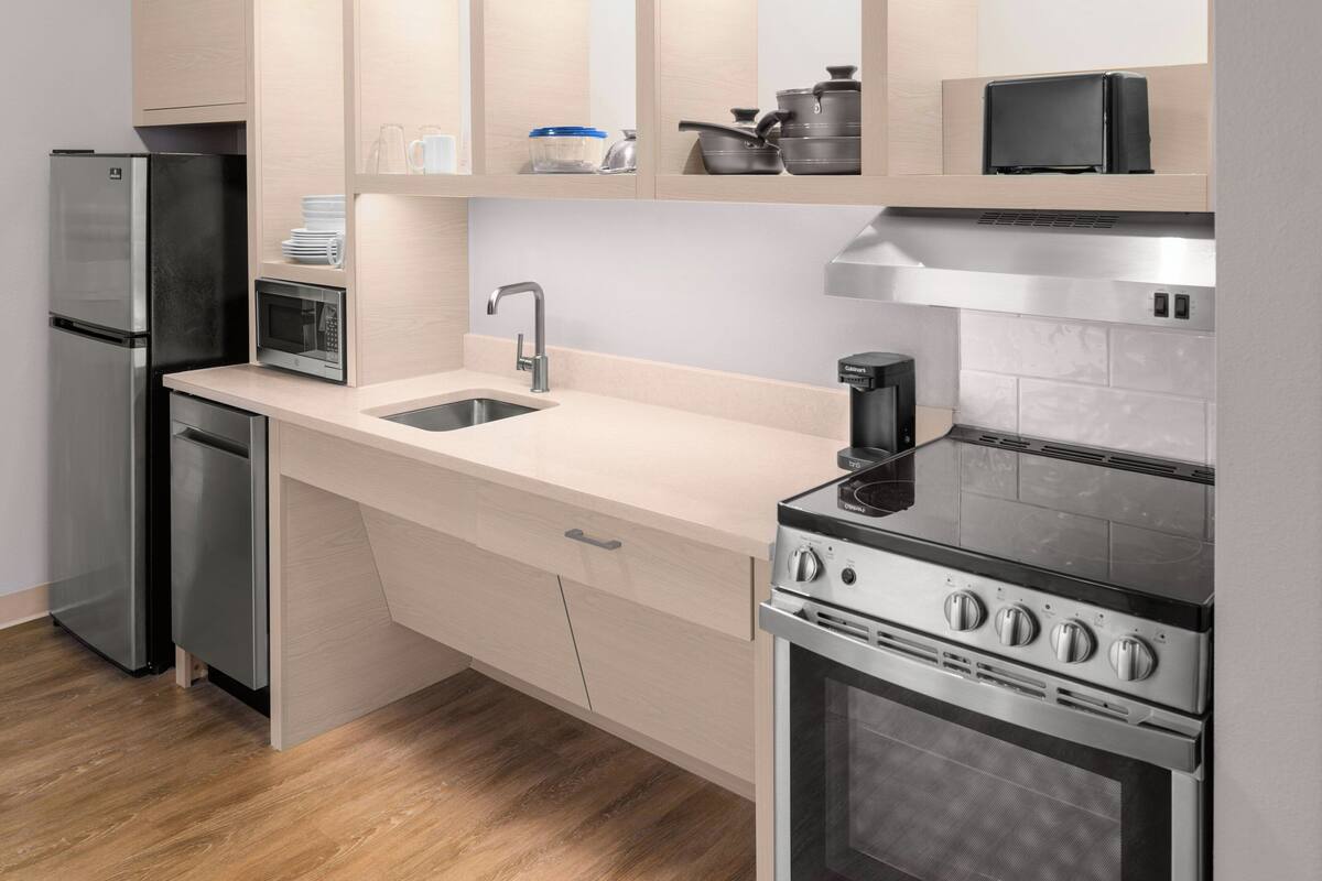 Una cocina moderna con electrodomésticos de acero inoxidable, microondas, lavaplatos y estufa.
