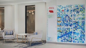 Un hall con un gran mapa mural, dos sillones, una mesa redonda y una alfombra estampada.