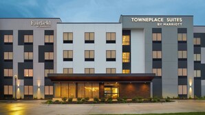 Un hotel moderno con la segnaletica 'Fairfield by Marriott' e 'Towneplace Suites by Marriott'. Presenta una facciata simmetrica con ampie finestre e un ingresso centrale.
