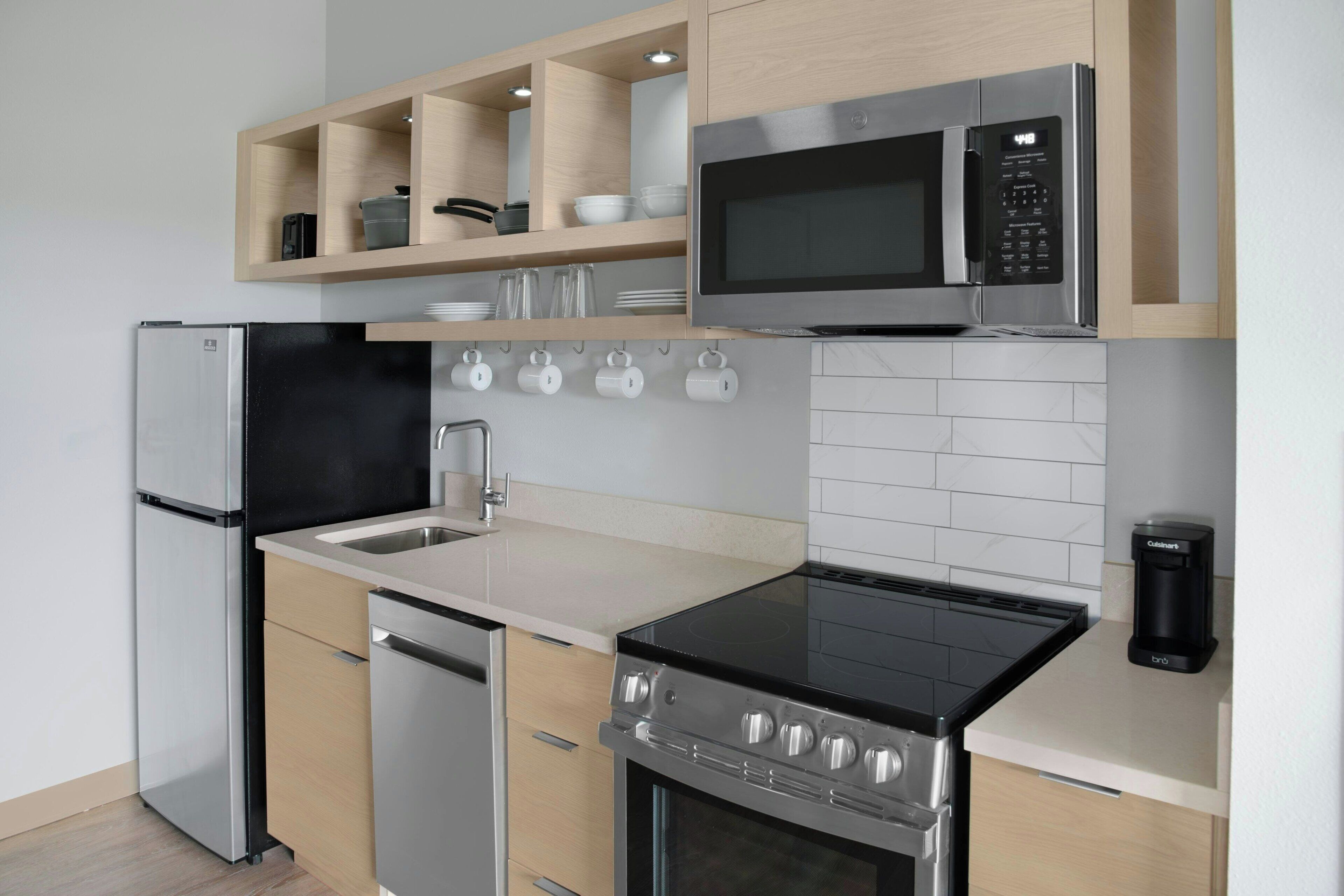 A modern kitchen with stainless steel appliances, wooden cabinets, and a white tiled backsplash.