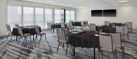 A conference room with round tables, chairs, and a carpeted floor.