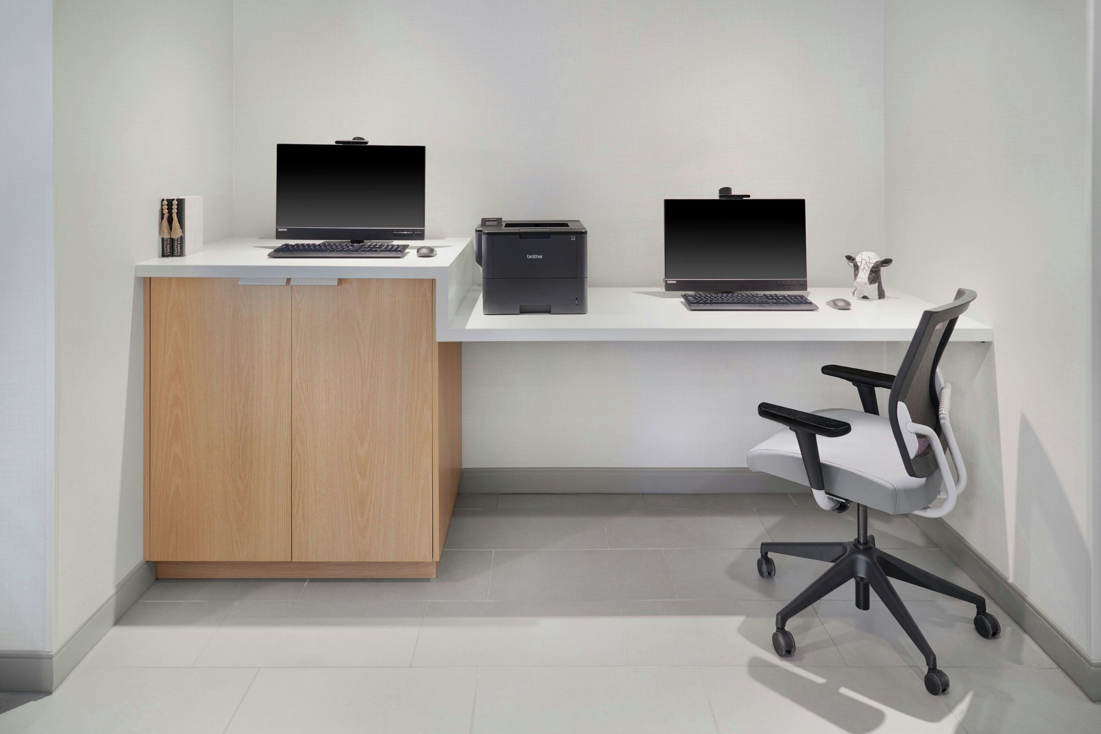 Een modern bureau met twee laptops, een printer en een stoel.