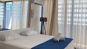 A hotel room with a large bed, a standing lamp, and a view of a building through sheer curtains. - orbi city apartments (Batumi)