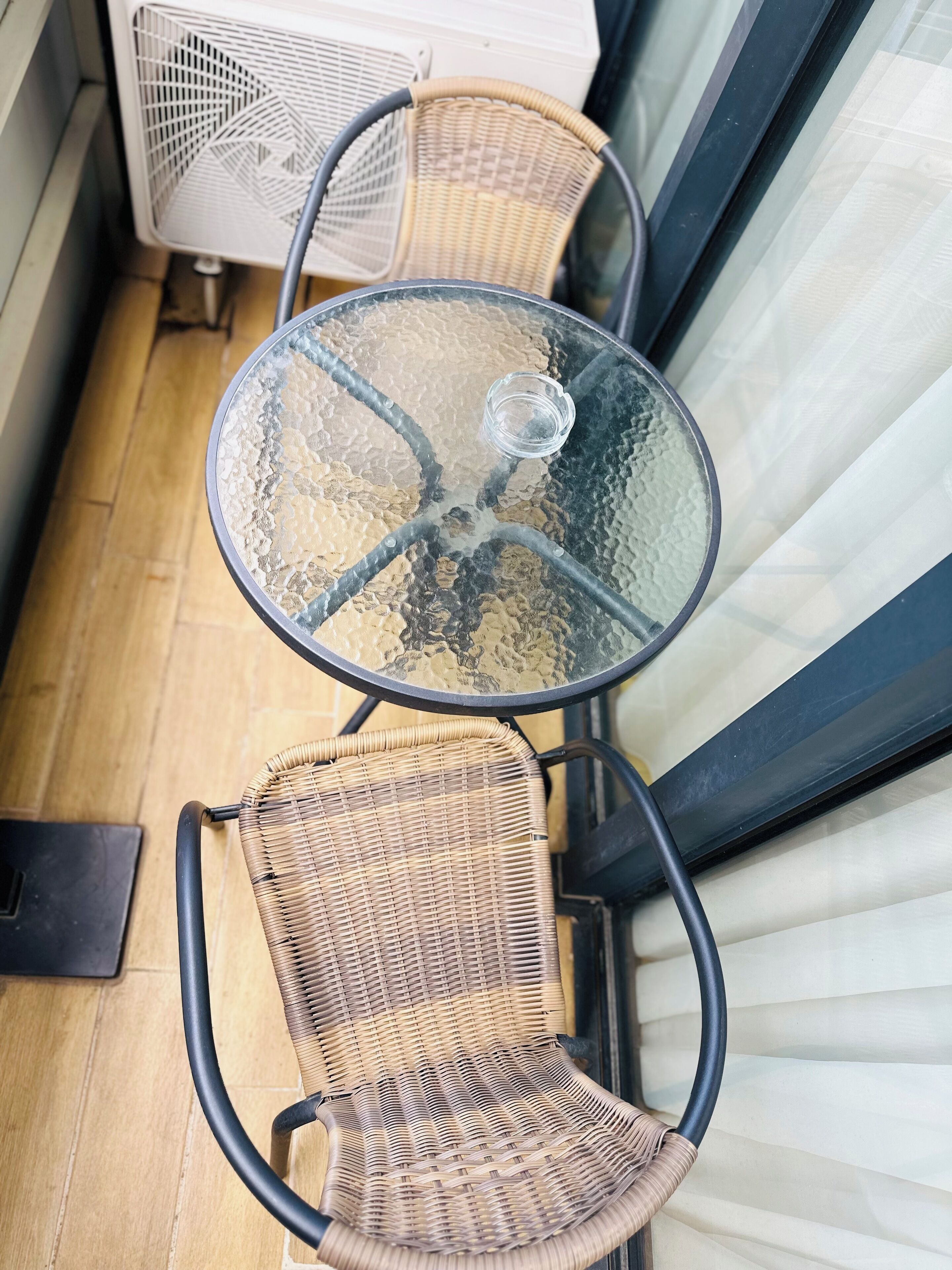A small glass-top table with two wicker chairs.