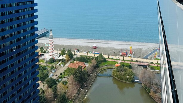 A high-rise building with a view of a coastal area, including a bridge and a body of water. - orbi city apartments (Batumi)