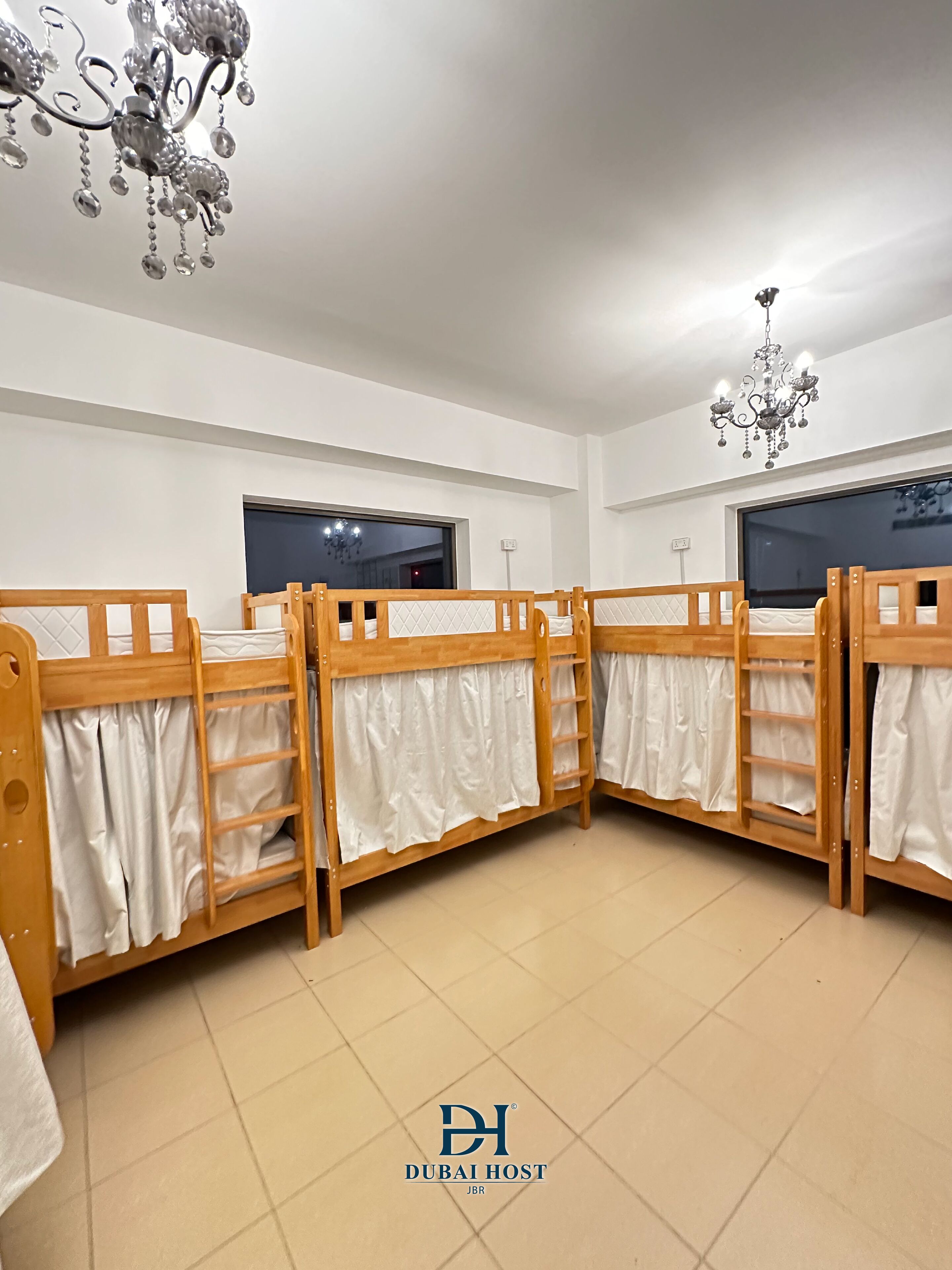 Une chambre d’hôtel avec quatre lits superposés en bois, un lustre et une grande fenêtre.