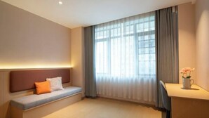 A hotel room with a bed, a bench with cushions, a desk with a chair, and a window with curtains. - Xiangrui Hotel (Hunan University of Technology Branch) (Zhuzhou)
