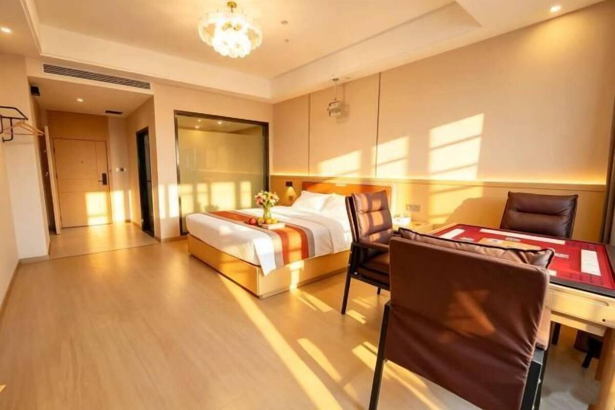 A hotel room with a bed, a desk, a chair, and a large window.