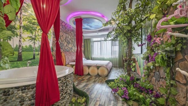 A room with a bathtub, a bed, and a stone wall with greenery. - Xiangrui Hotel (Hunan University of Technology Branch) (Zhuzhou)