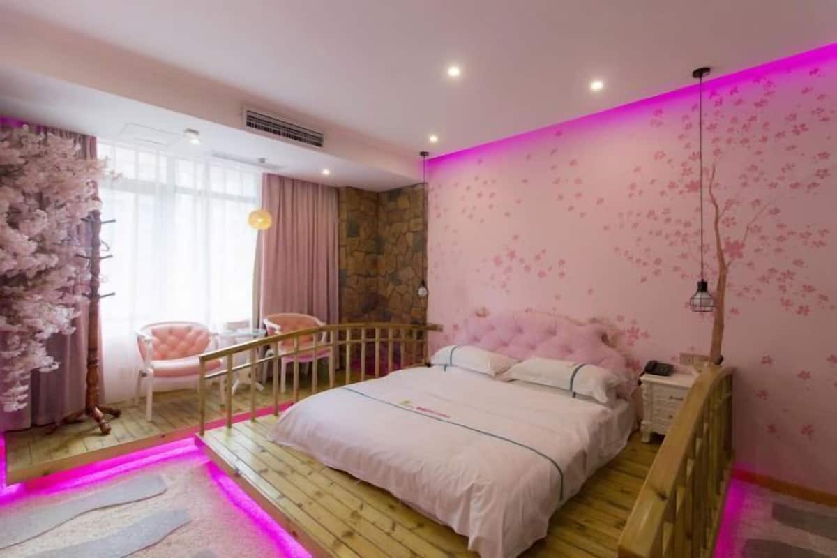 A bedroom with a bed, a chair, a nightstand, and a staircase.