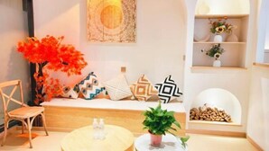 A cozy seating area with a bench, a round wooden table, a chair, a wall-mounted tapestry, and a shelf with decorative items. - Xiangrui Hotel (Hunan University of Technology Branch) (Zhuzhou)