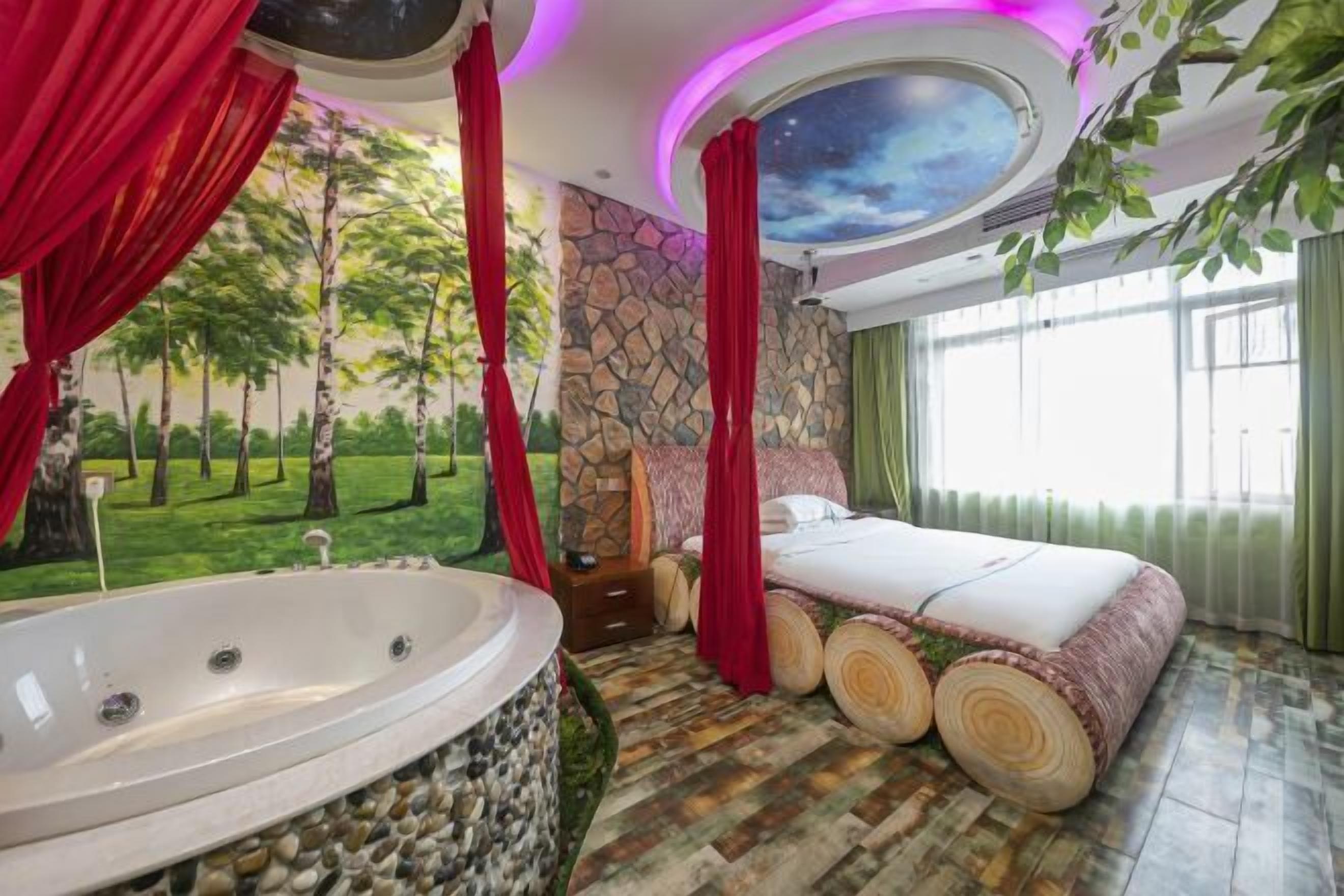 Ein Schlafzimmer mit einer großen Badewanne, einem Bett mit Holz-Kopfteil und einem Wandgemälde von Bäumen.