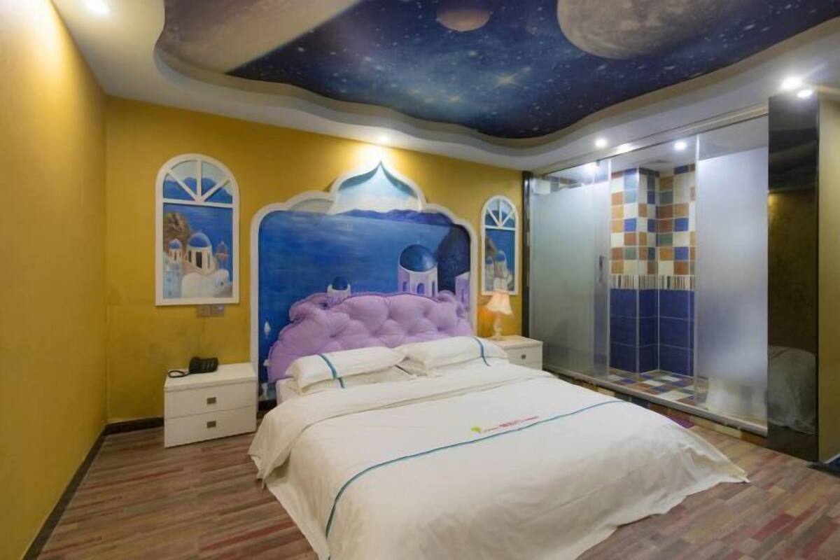 A bedroom with a bed, nightstands, a vanity, and a mirror.