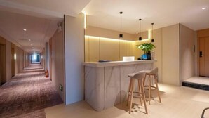 A modern hotel corridor with a marble bar area featuring two bar stools and pendant lighting. - Xiangrui Hotel (Hunan University of Technology Branch) (Zhuzhou)