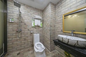 Un baño con diseño de pared de piedra, un inodoro, una ducha y un lavabo con un espejo grande.