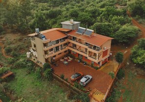 Um edifício de vários andares com telhado plano, painéis solares e um pátio pavimentado com área de estar externa.