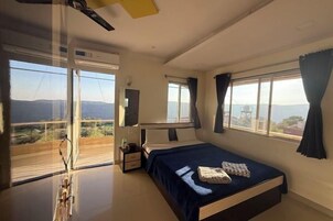 Un dormitorio con cama, mesita de noche, espejo y ventana con cortinas.