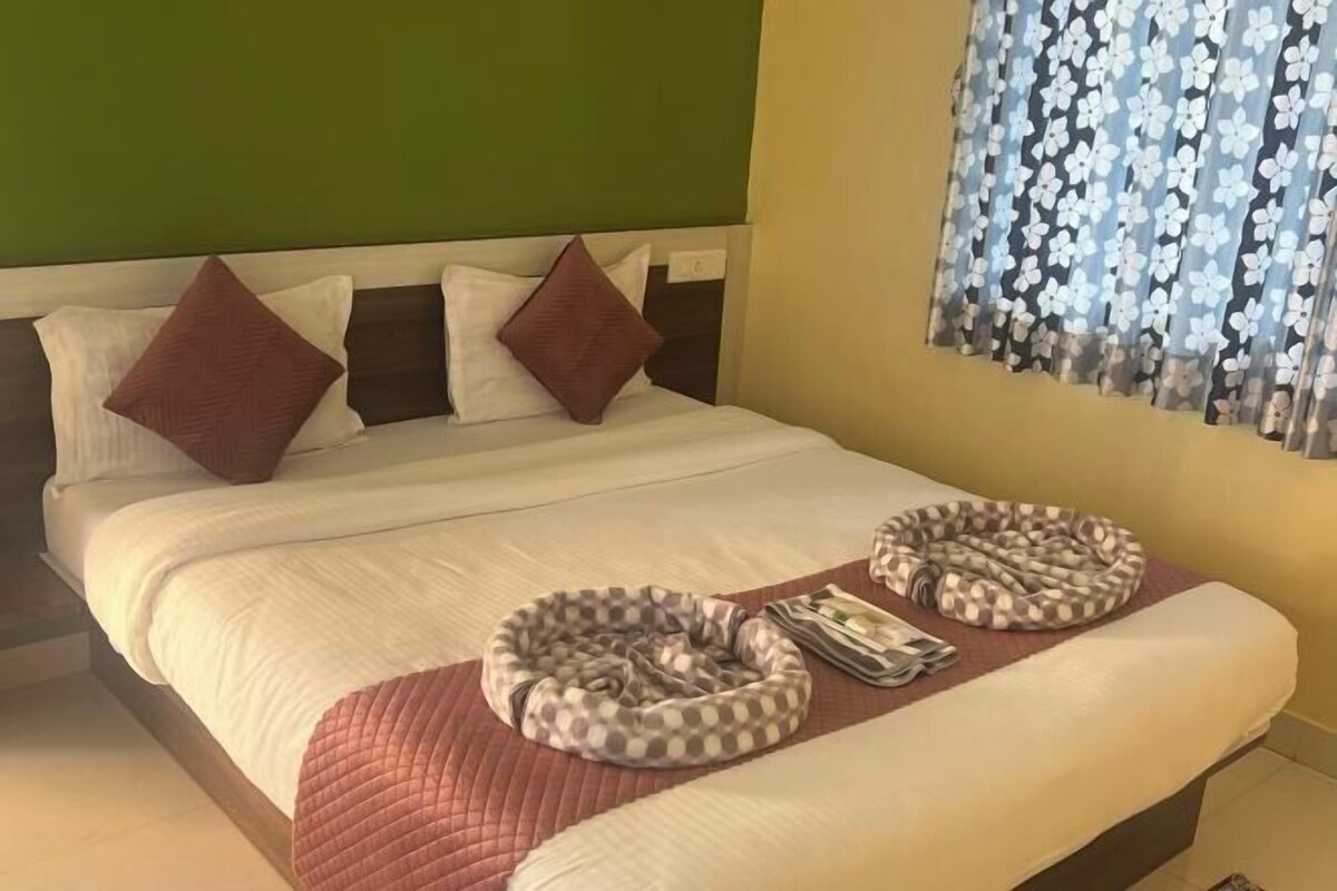 Cama bem arrumada com colcha acolchoada, dois travesseiros e dois pufes redondos sobre um cobreleito combinando.