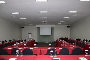 A conference room with multiple tables, chairs, and a projector screen. - 100 Sunset Kuta Hotel & Ballroom (Bali)
