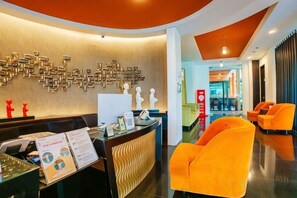 A reception area with a modern design, featuring a reception desk, seating area, and a wall with a geometric pattern. - 100 Sunset Kuta Hotel & Ballroom (Bali)