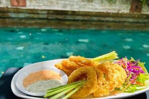 A plate of breaded and fried food with a side of dipping sauce and a small salad. - 100 Sunset Kuta Hotel & Ballroom (Bali)