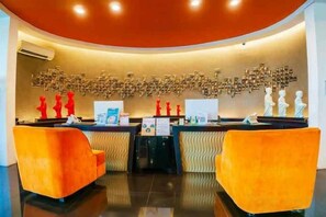 A reception area with a curved ceiling, a reception desk, and two orange chairs. - 100 Sunset Kuta Hotel & Ballroom (Bali)