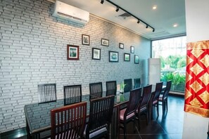 A modern interior with a brick wall, framed pictures, and a glass table with chairs. - 100 Sunset Kuta Hotel & Ballroom (Bali)