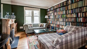 Un salón acogedor con sofá, mesa de centro, chimenea y una amplia estantería llena de libros.