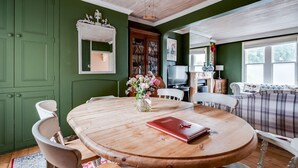 Un comedor con una mesa de madera, sillas y un jarrón de flores.