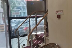 Una escalera con barandilla que conduce a un ventanal con vistas a la calle.