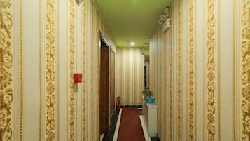 A hallway with patterned wallpaper, a red carpet, and a door at the end.