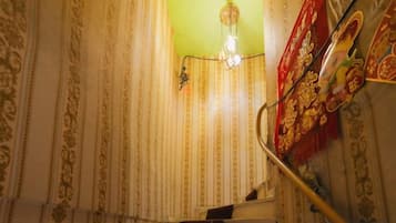 A staircase with patterned wallpaper and a decorative red banner.