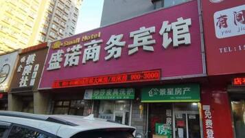 A hotel with a prominent red signboard advertising business services.