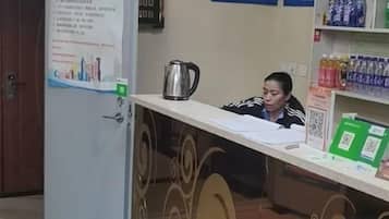 A reception desk with a kettle, papers, and a QR code.