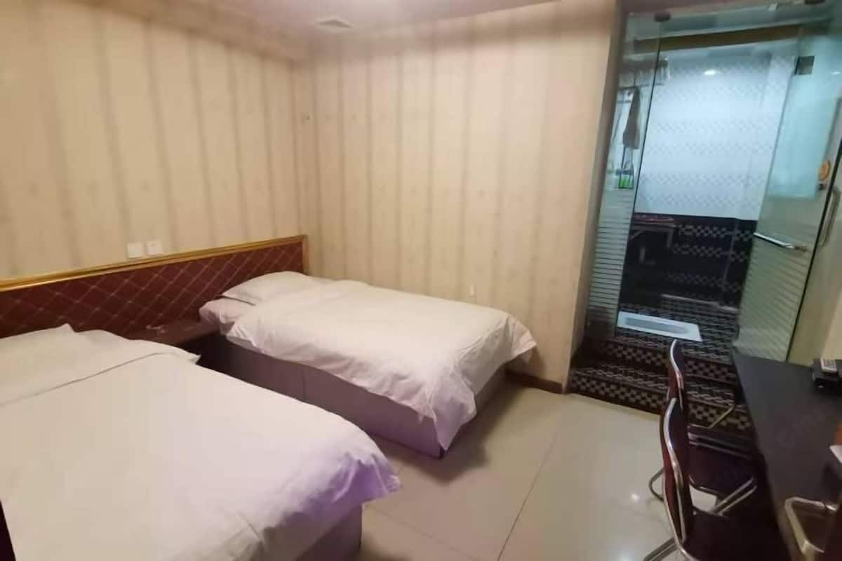 A hotel room with two beds, a desk, and a chair.