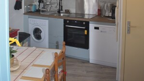 A compact kitchen with grey cabinets, a washing machine, a dishwasher, and a hanging light fixture.