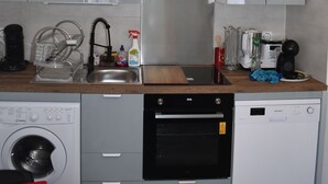A compact kitchen with grey cabinets, a built-in oven, a dishwasher, and a coffee maker.