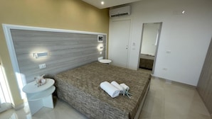 A modern bedroom with a large bed, bedside table, and a mirror. - B&B Jerocades (Parghelia)